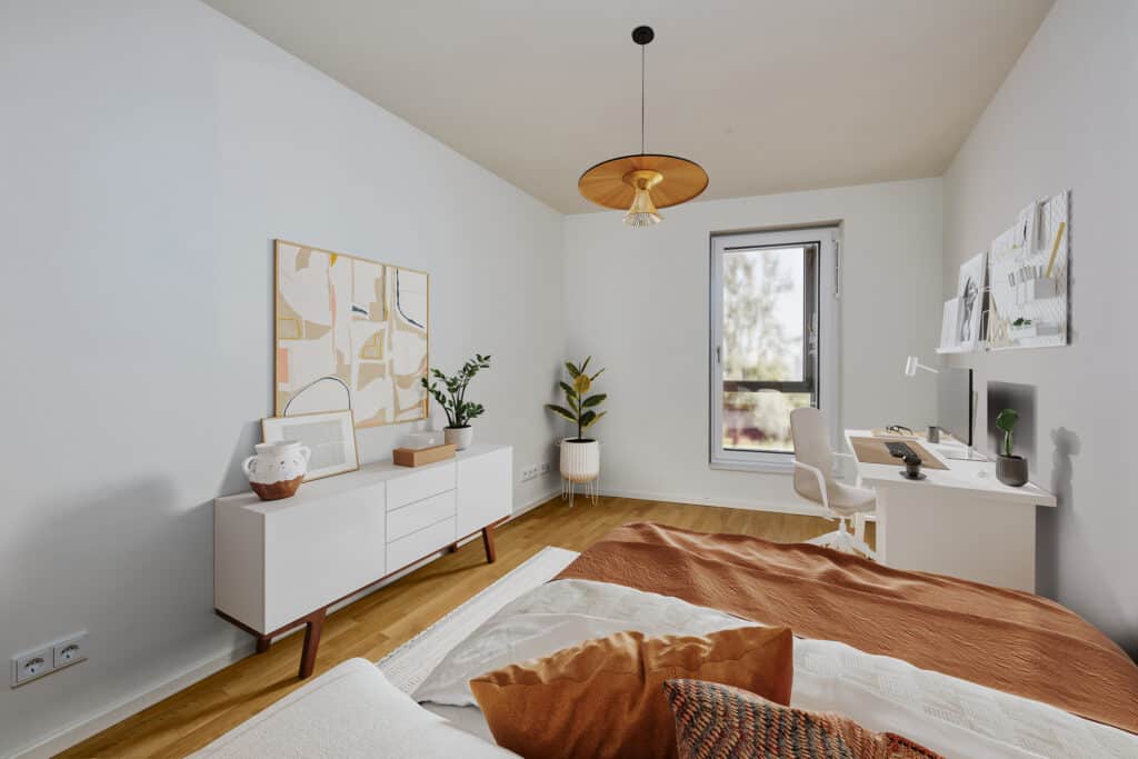 Helles Schlafzimmer mit modernem Sideboard, stylischem Kunstwerk, warmen Textilien und praktischem Arbeitsplatzbereich in zeitgemäßem Wohnungsdesign.